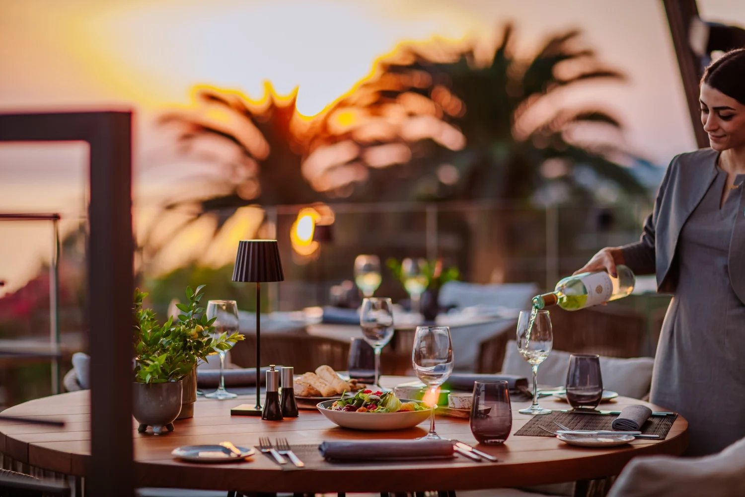 Kıbrıs'ta çok güzel bir otel manzarasında kadehe şarap dolduran kız. Şarap, yiyecek ve pastaların bulunduğu restoran masası. Kıbrıs turu rezervasyonu için Kıbrıs'ın Lefkoşa merkezinde.