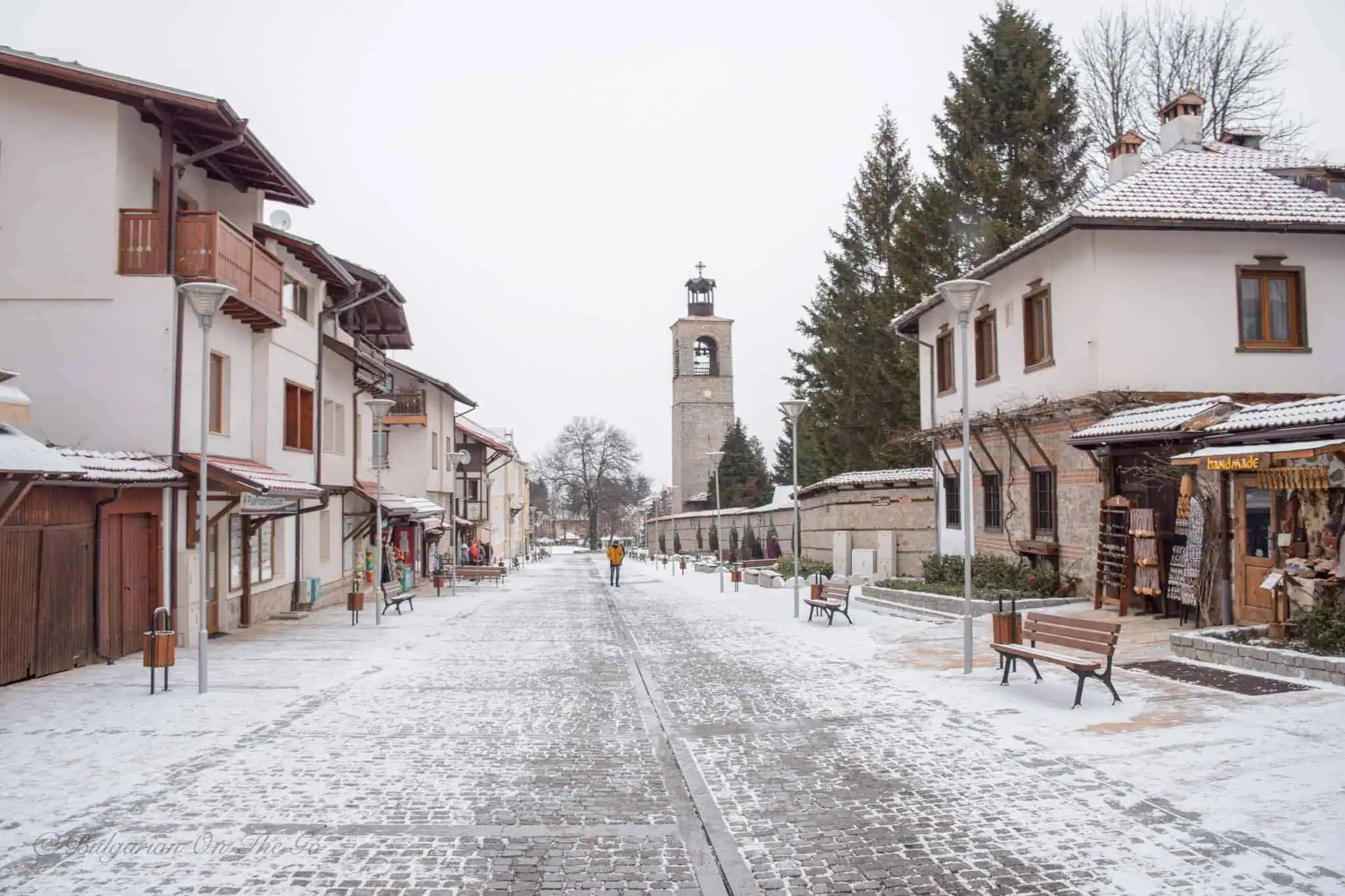 Bansko'nun tarihi eski şehir sokaklarında gezinti yapan turistler. Geleneksel Bulgar mimarisi ve taş döşeli yollar ile dolu bir atmosfer. Ramazan-Bayrami-Turlari-2025-Kisin-Keyfini-Cikarin-Bansko-Bulgaristanin-Kis-Cenneti